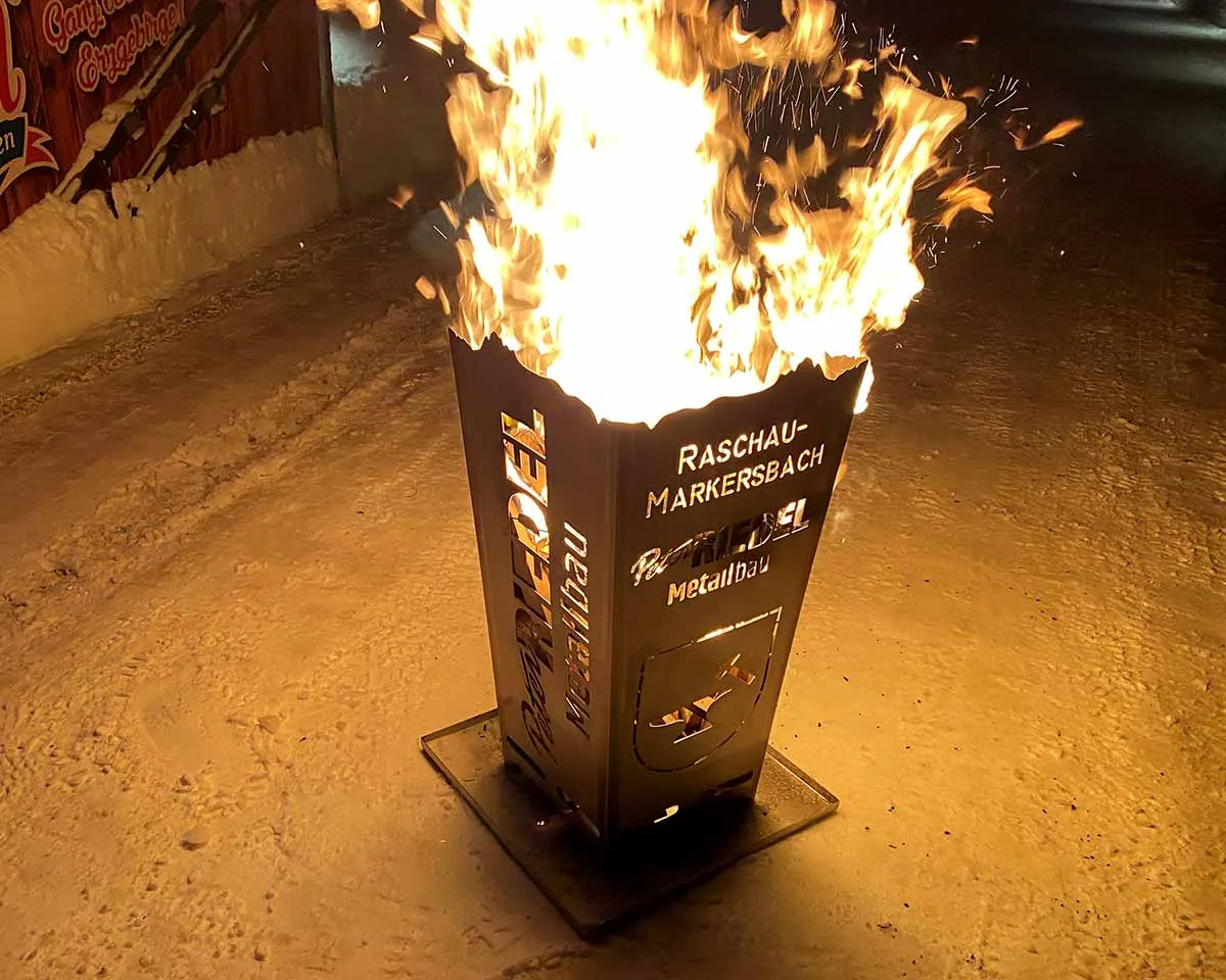 Brennender Feuerkorb aus Stahl bei Nacht im Schnee